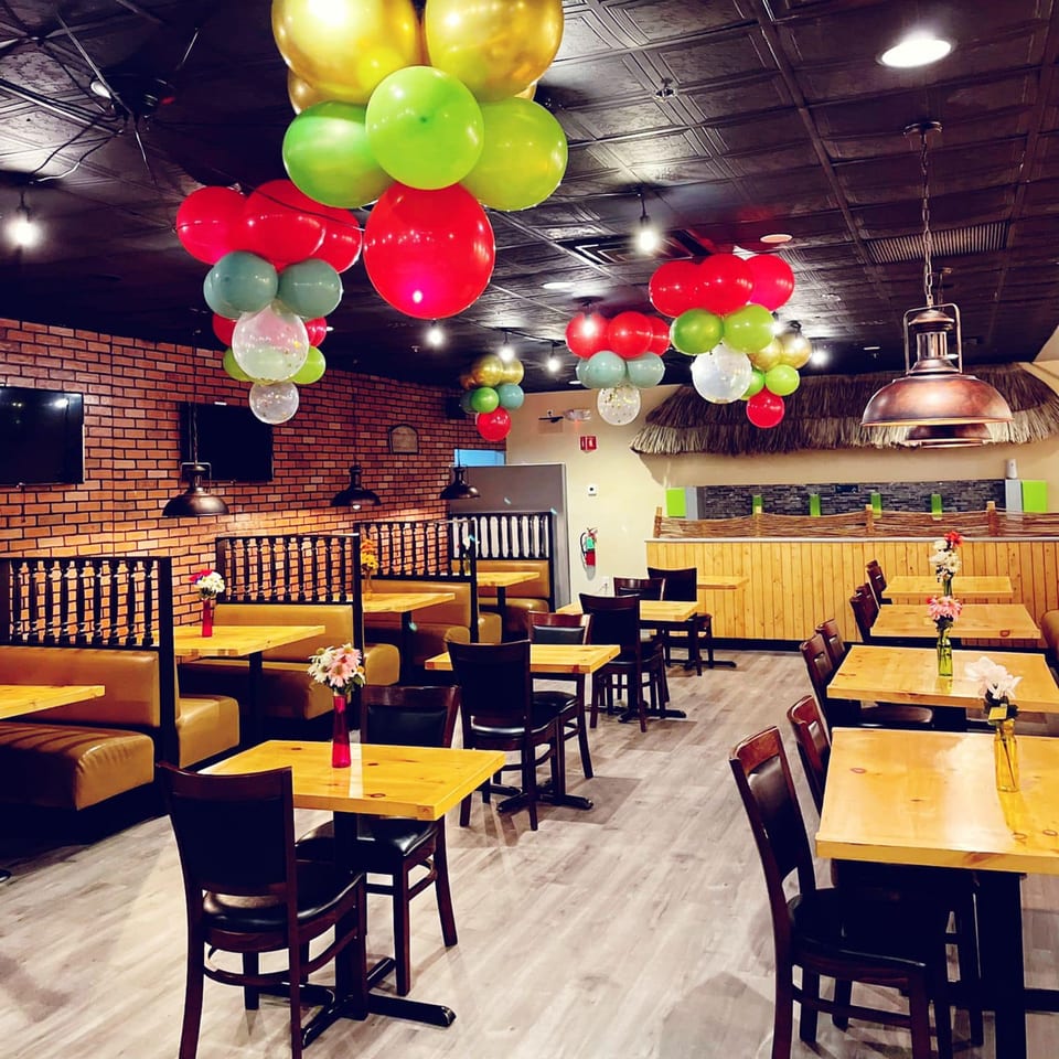 The Peppers Indian Cuisine dining room features festive balloons, wooden tables, and booth seating.