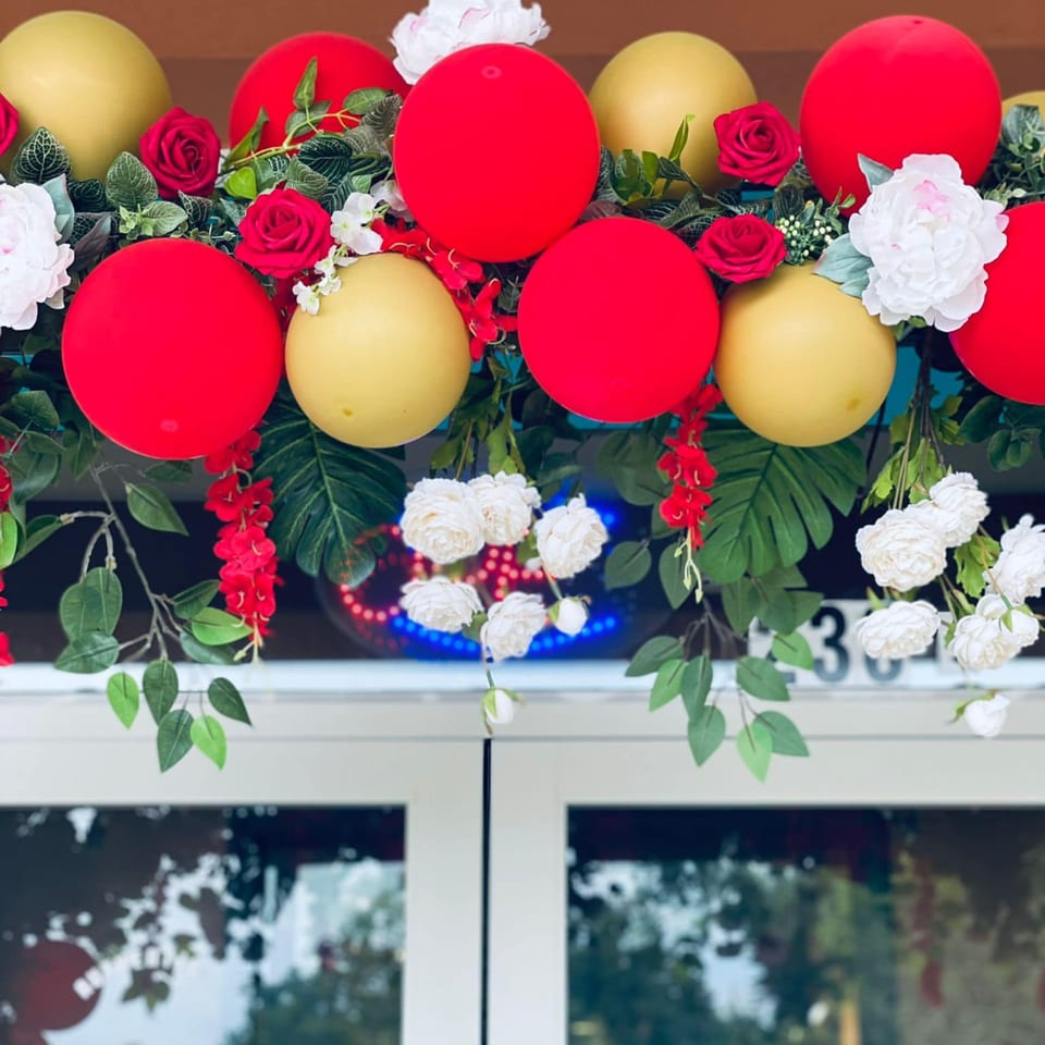 Red and gold balloons with red roses and white flowers adorn the entrance of Peppers Indian Cuisine.